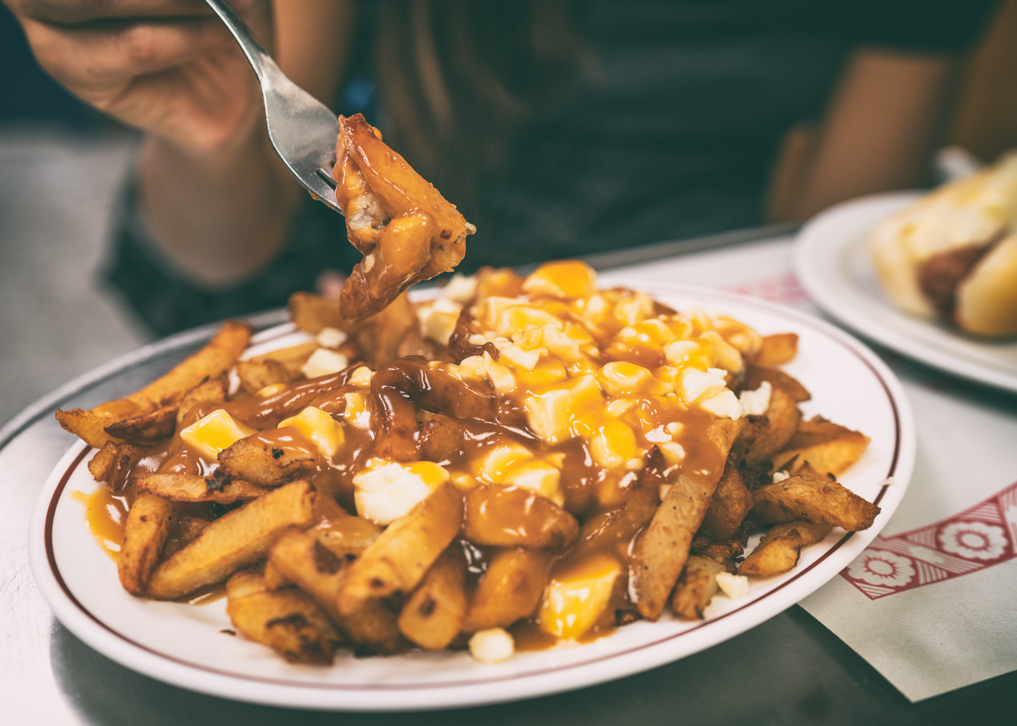 Poutine french fries canadian local classic dish in the province of Quebec, Canada. Fast food retro diner restaurant serving plate of fried potates with brown gravy sauce and fresh cheese curds.